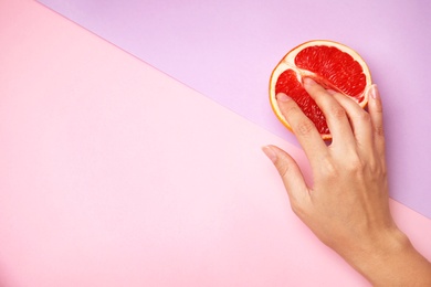 Young woman touching half of grapefruit on color background, top view with space for text. Sex concept