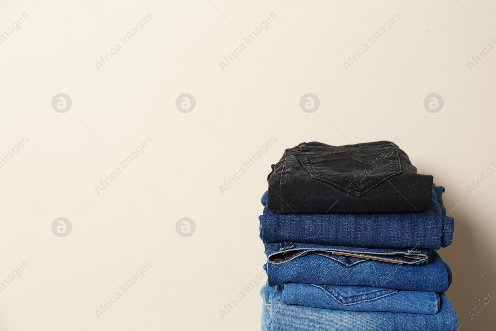 Photo of Stack of different jeans against light background