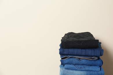 Photo of Stack of different jeans against light background