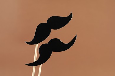 Photo of Fake paper mustaches party props on light brown background