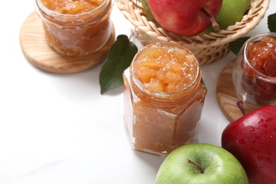 Delicious apple jam and fresh fruits on white table, space for text