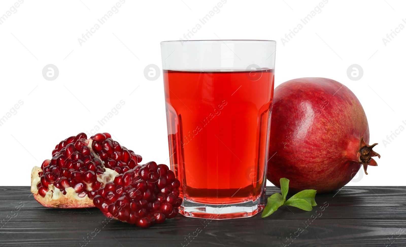 Photo of Refreshing pomegranate juice in glass, leaves and fruits on black wooden table against white background