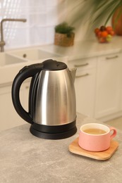 Photo of Electric kettle and cup on table in kitchen