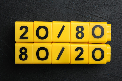 Photo of Yellow blocks with numbers 20 and 80 on black stone background, flat lay. Pareto principle concept