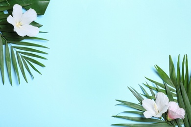 Photo of Flat lay composition with tropical leaves and Hibiscus flowers on blue background. Space for text