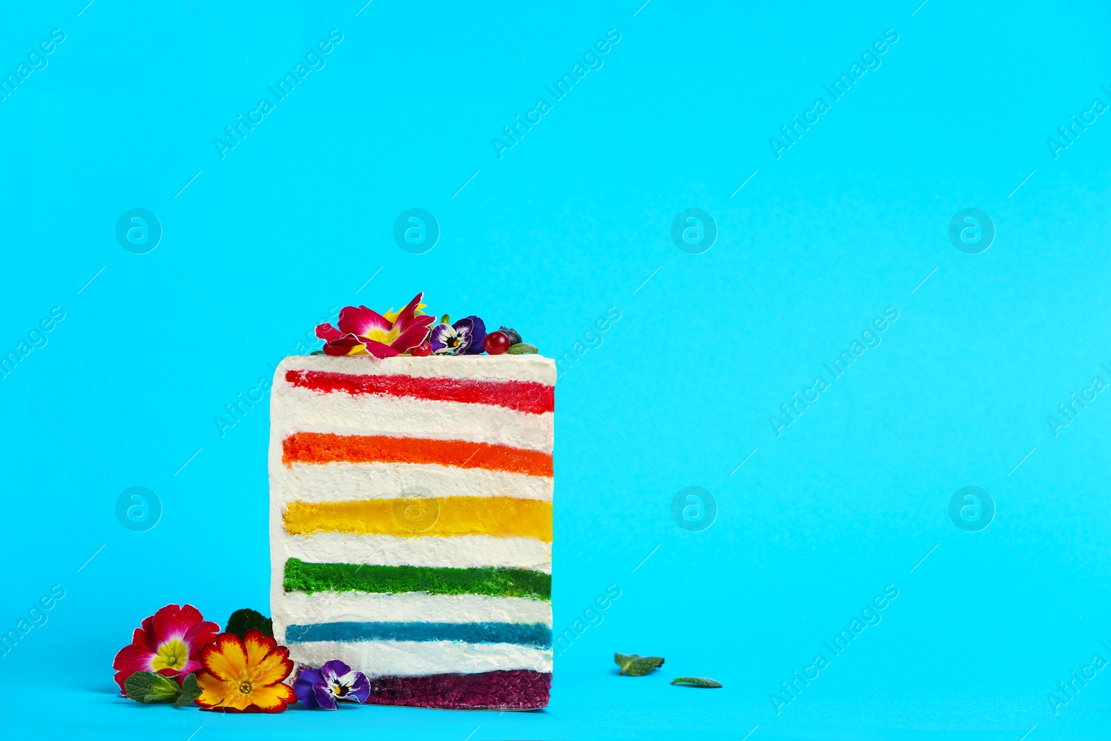 Photo of Slice of delicious rainbow cake with flowers on color background