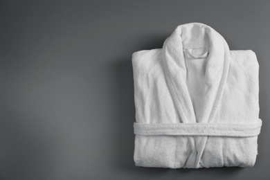 Photo of Clean folded bathrobe on grey background, top view. Space for text