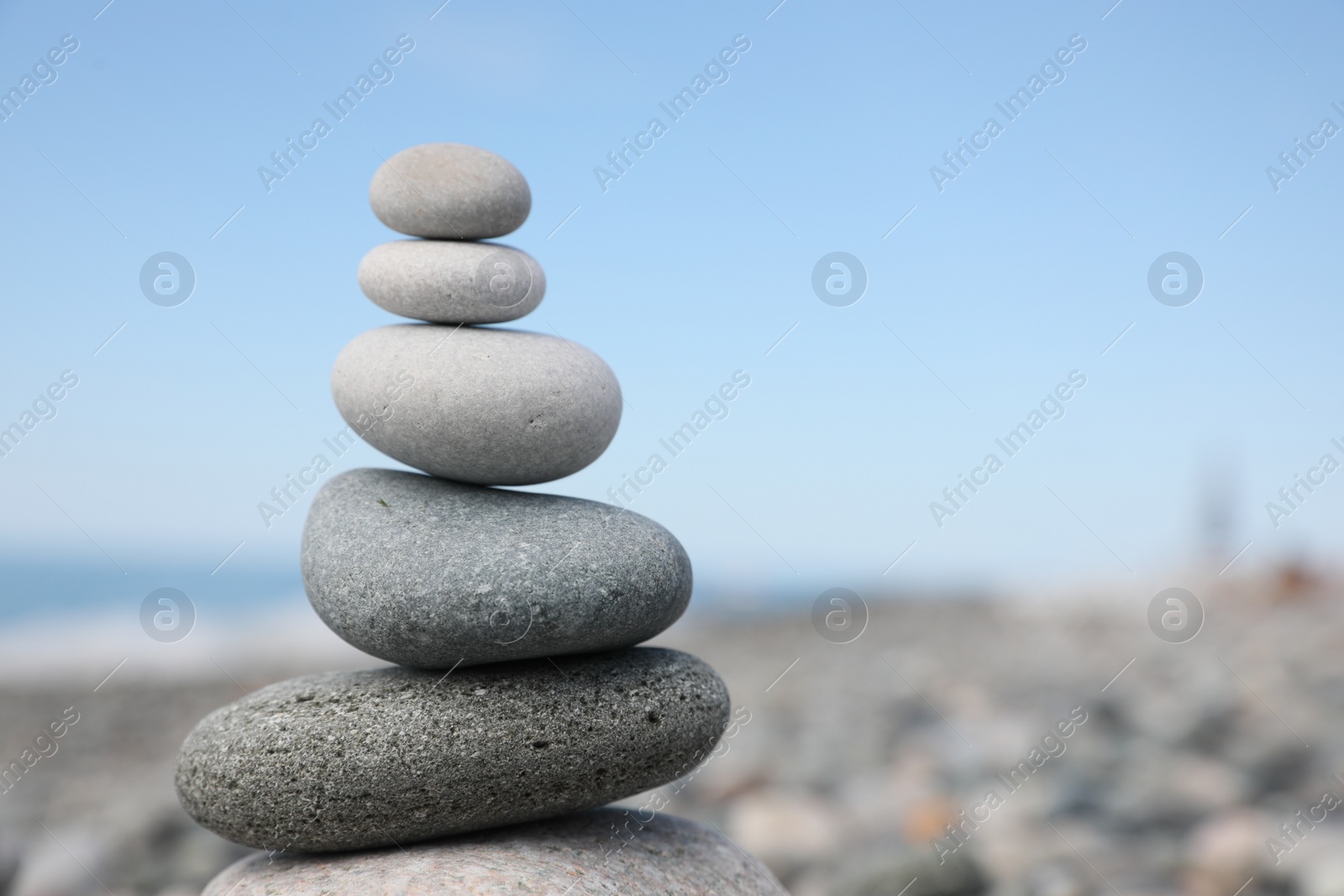 Photo of Stack of stones on beach against blurred background, closeup. Space for text