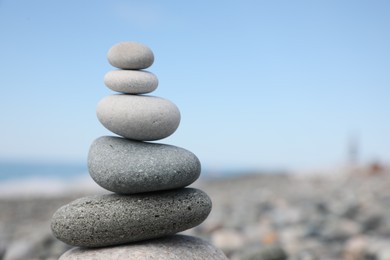 Photo of Stack of stones on beach against blurred background, closeup. Space for text