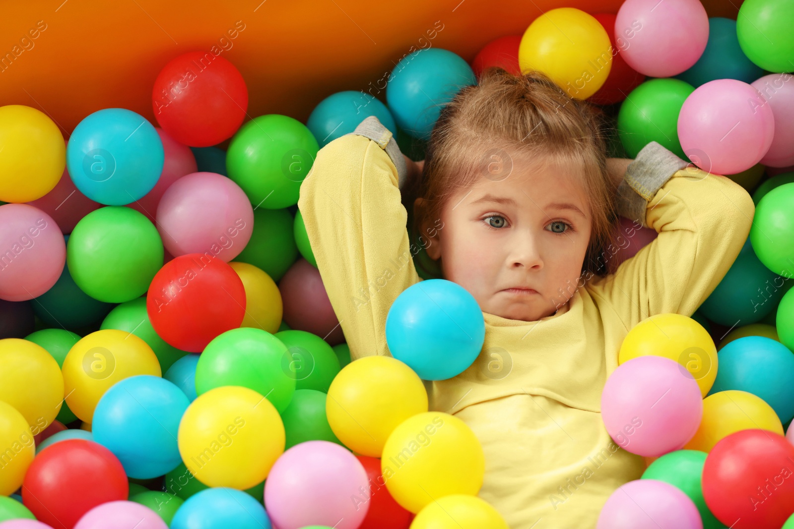 Photo of Cute little child playing in ball pit at indoor amusement park