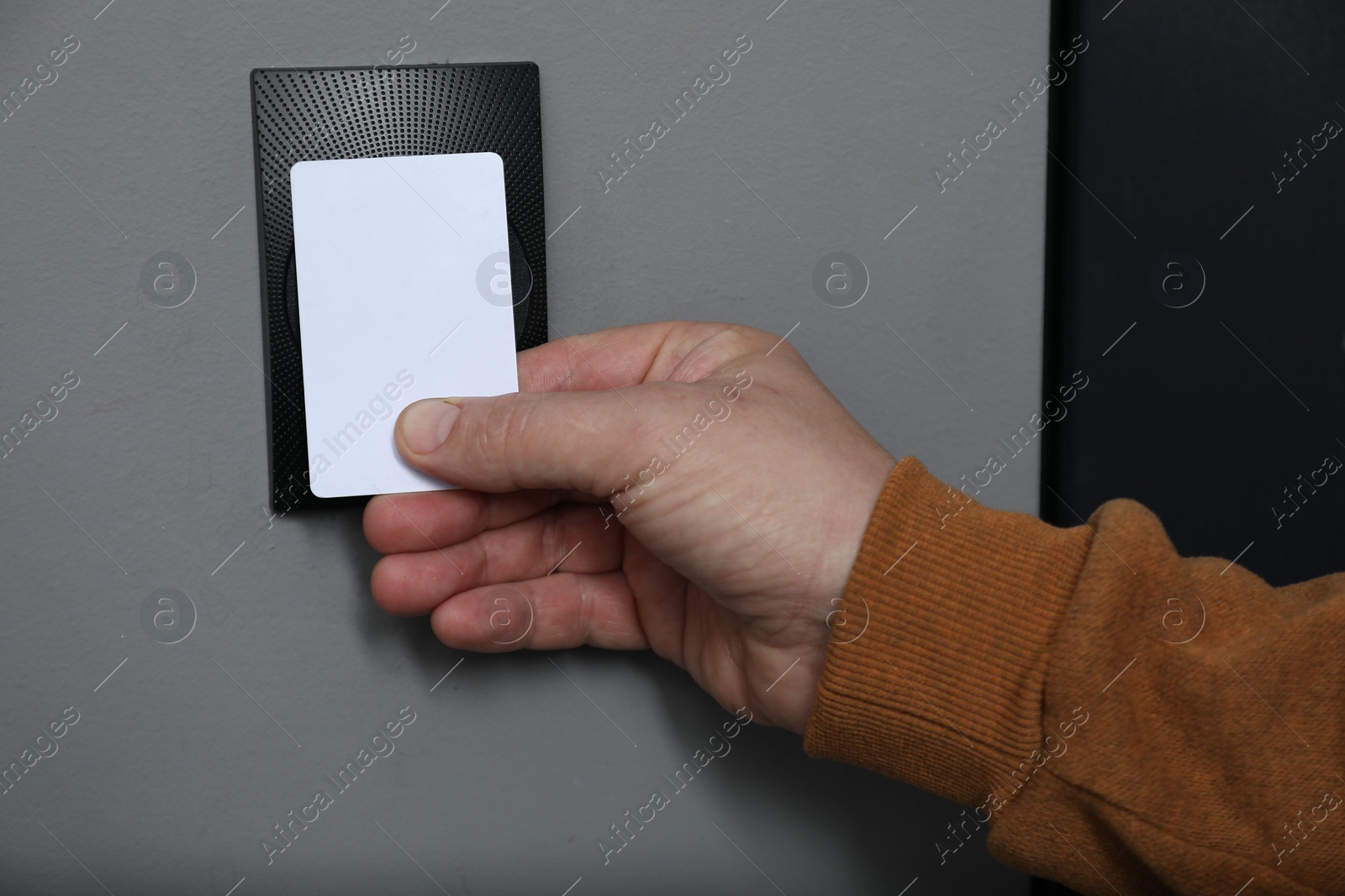 Photo of Man opening magnetic door lock with key card, closeup. Home security