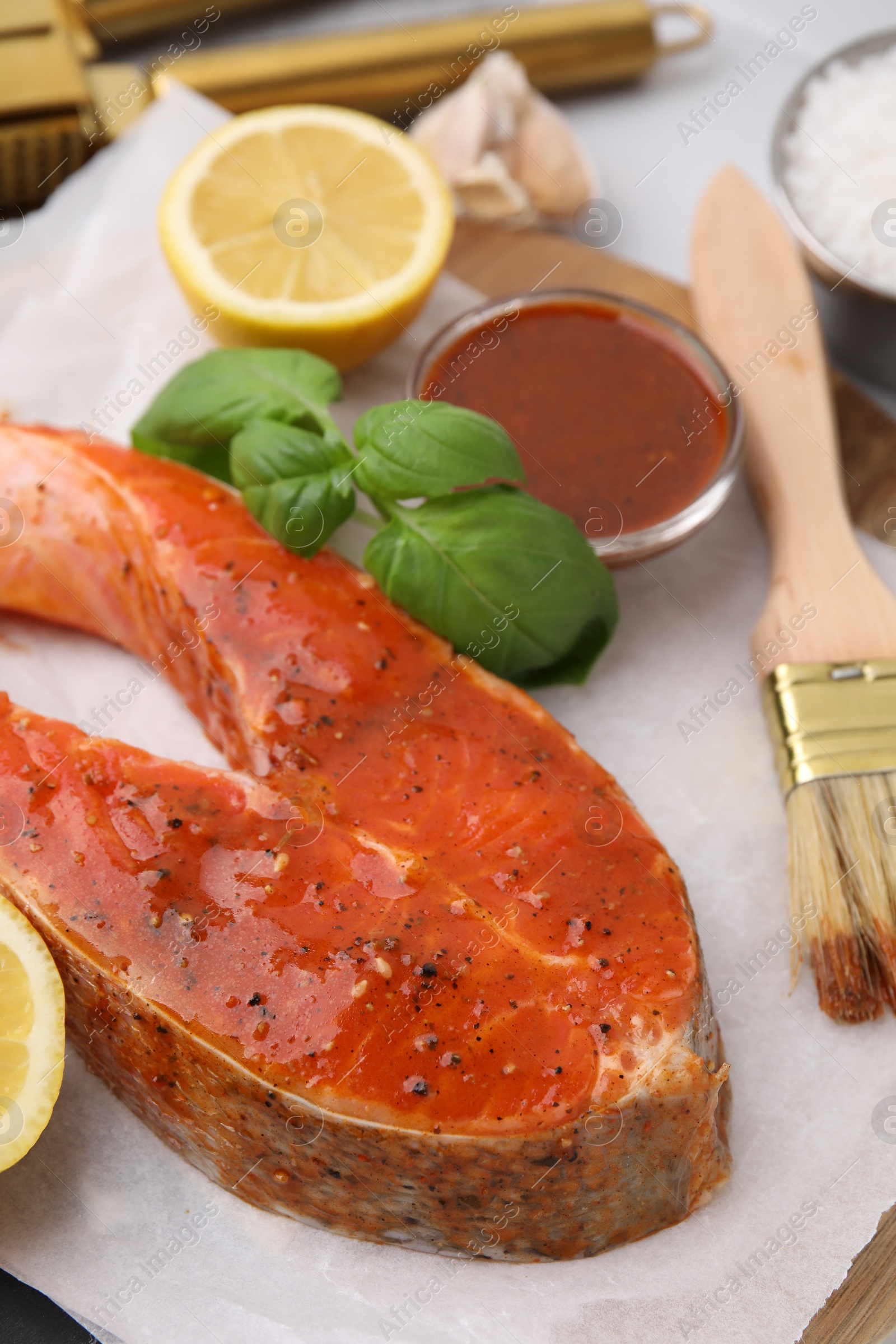 Photo of Fresh marinade, fish, lemon, brush and basil on table, closeup