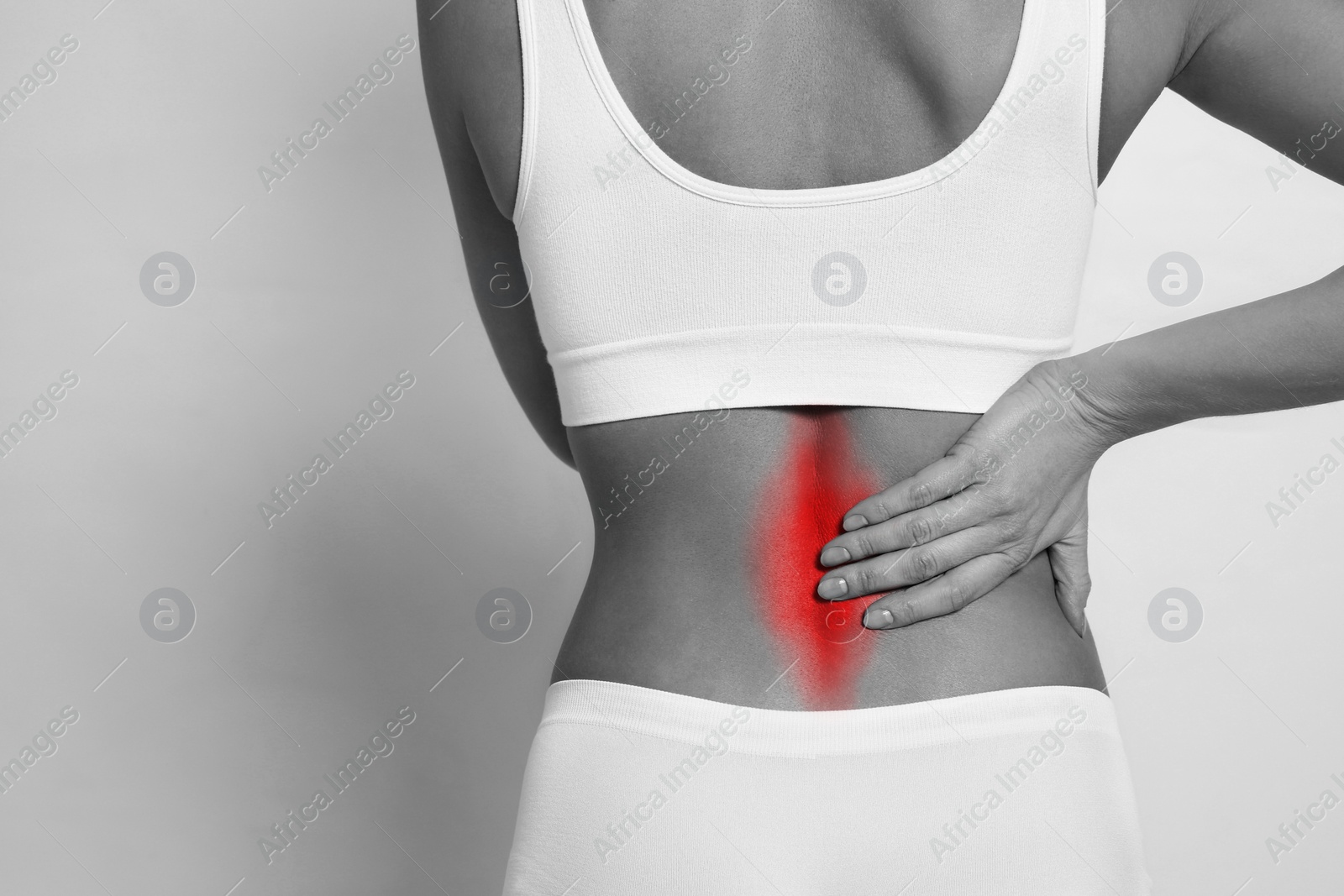 Image of Woman suffering from back pain on light background, closeup