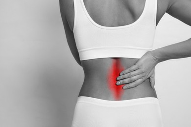 Image of Woman suffering from back pain on light background, closeup