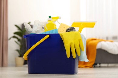 Photo of Different cleaning supplies in bucket on floor at home