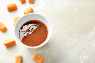 Photo of Delicious caramel candies and sauce on light background