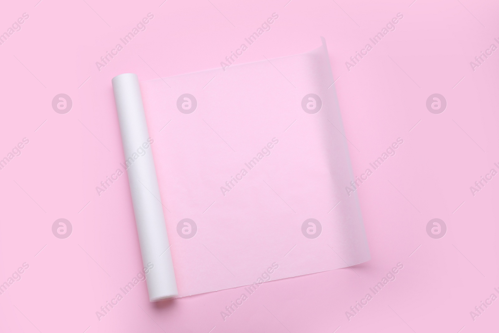 Photo of Roll of baking paper on pink background, top view