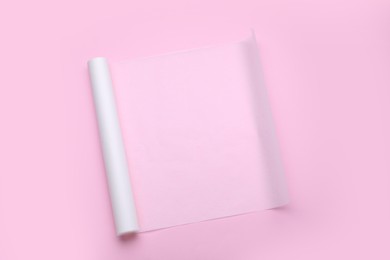 Roll of baking paper on pink background, top view