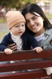 Family portrait of happy mother and her baby on bench in park