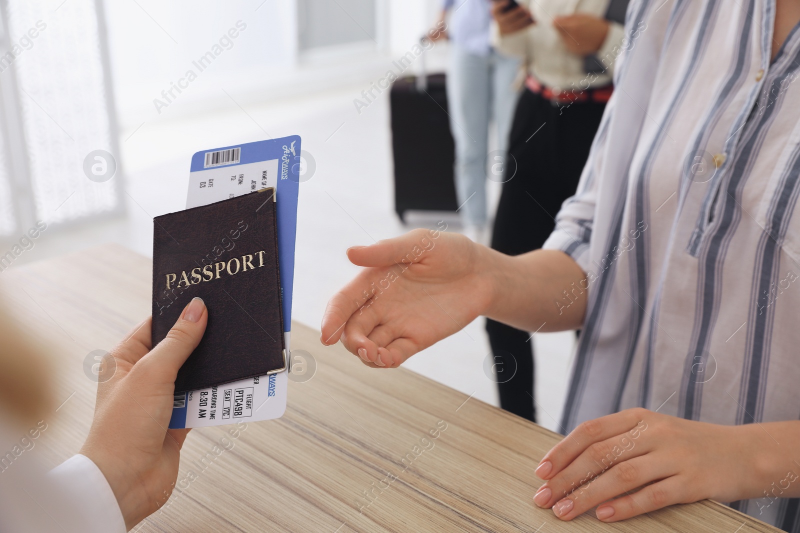 Photo of Agent giving passport with ticket to client at check-in desk in airport, closeup