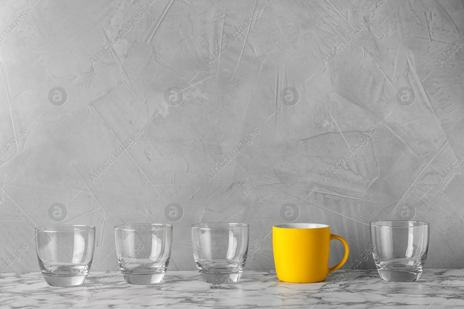 Photo of Row of glasses with bright cup on table. Be different