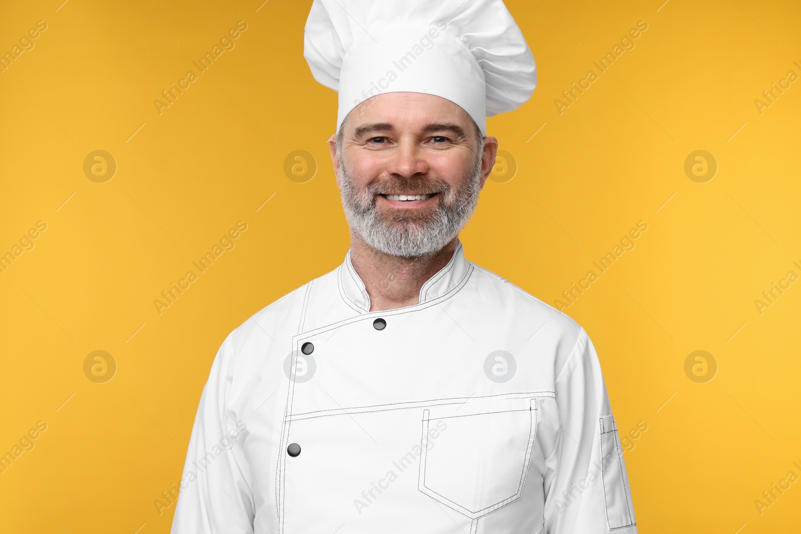 Photo of Happy chef in uniform on orange background