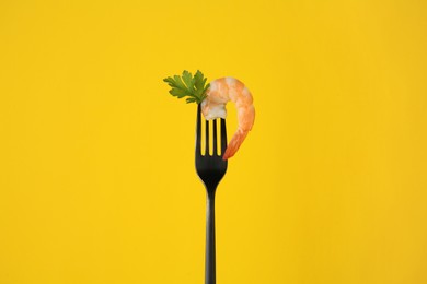 Fork with shrimp and parsley on yellow background