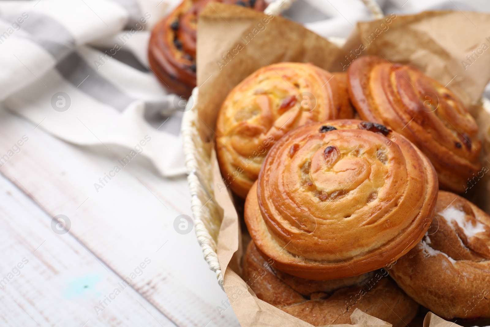 Photo of Delicious rolls with raisins on white wooden table, closeup and space for text. Sweet buns