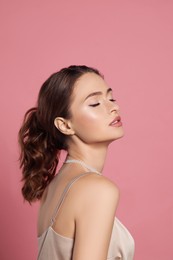 Photo of Young woman wearing elegant pearl necklace on pink background