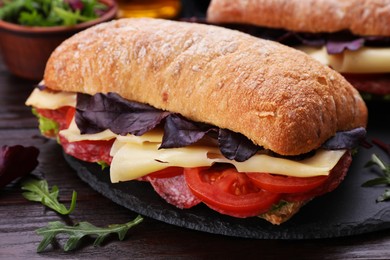 Photo of Delicious sandwich with cheese, salami, tomato on wooden table, closeup