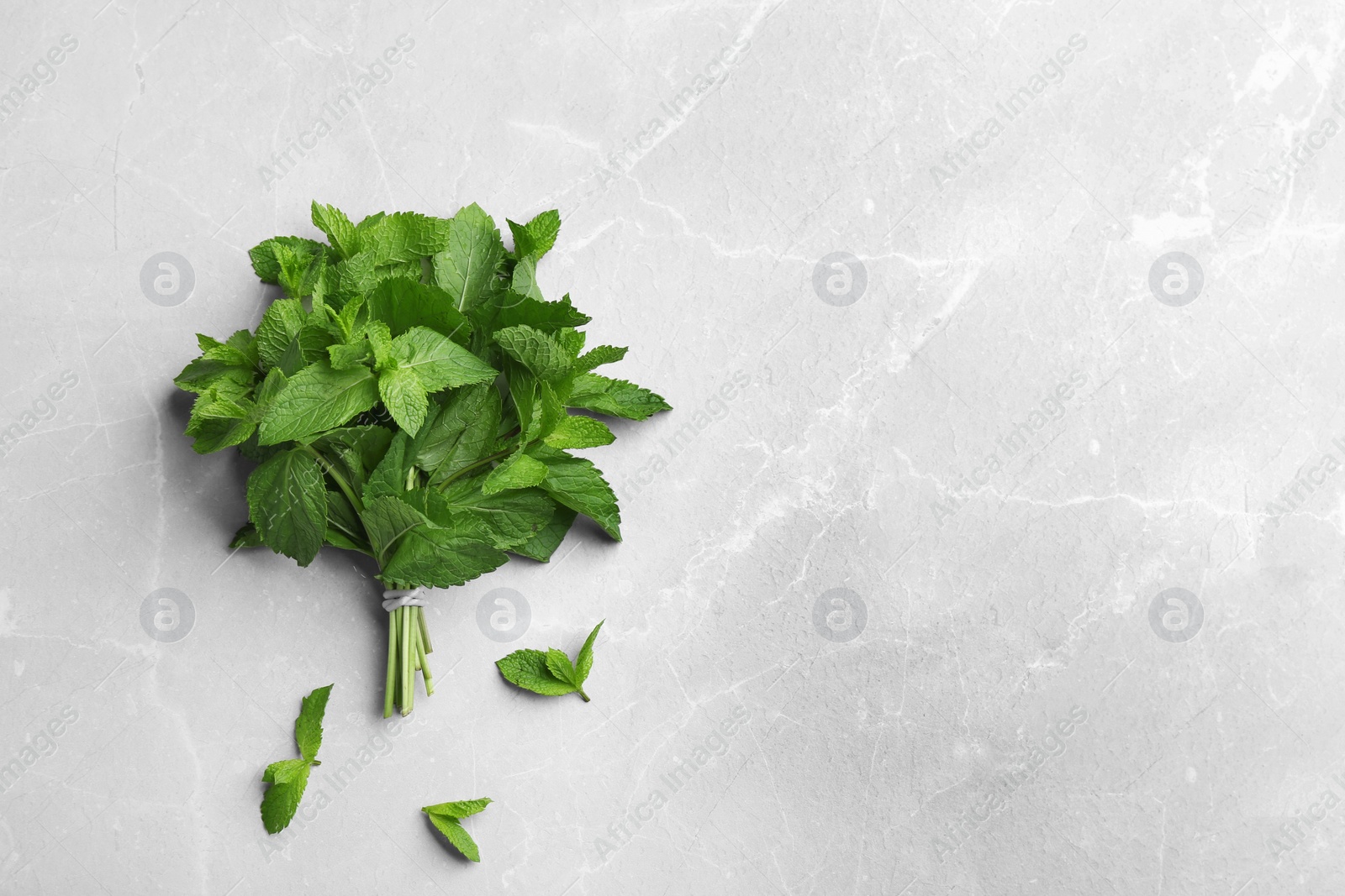 Photo of Bunch of fresh mint on grey marble  background, top view. Space for text