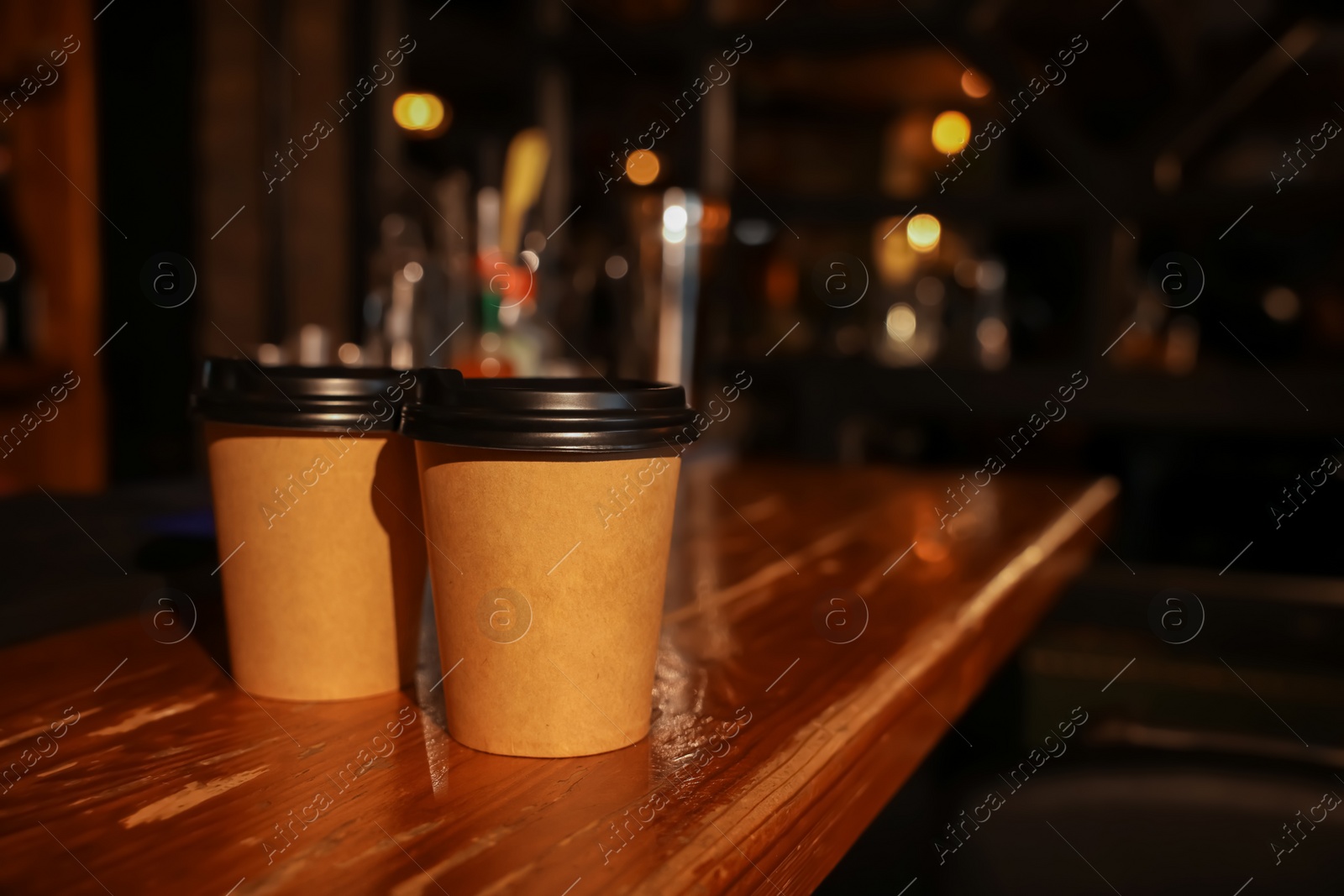 Photo of Paper coffee cups on wooden table in cafe. Space for text