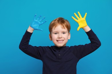Photo of Little boy with hands painted in Ukrainian flag colors on light blue background. Love Ukraine concept