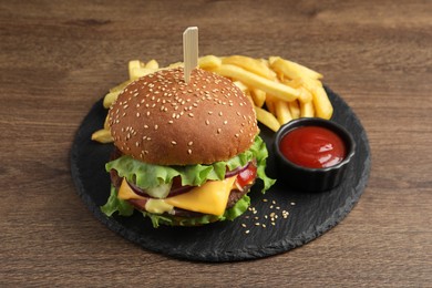 Delicious burger with beef patty, tomato sauce and french fries on wooden table