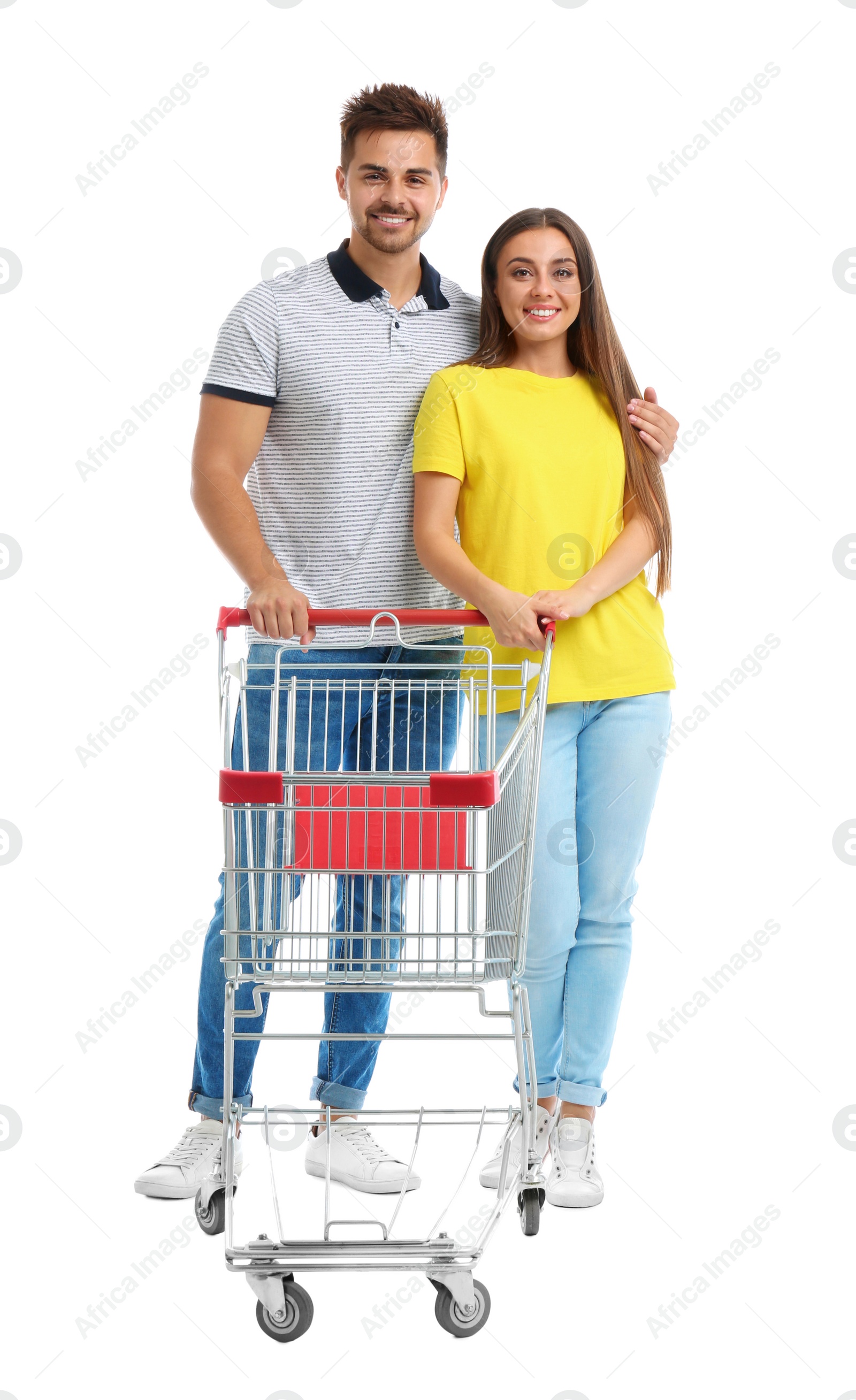 Photo of Young couple with empty shopping cart on white background