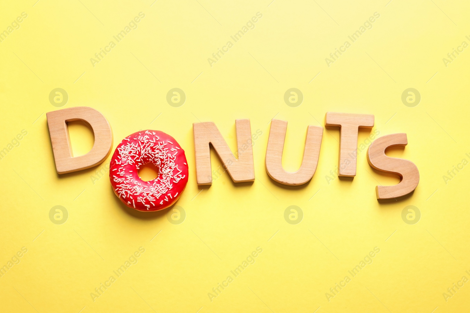 Photo of Flat lay composition with word "Donuts" on color background