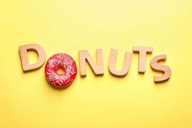 Photo of Flat lay composition with word "Donuts" on color background