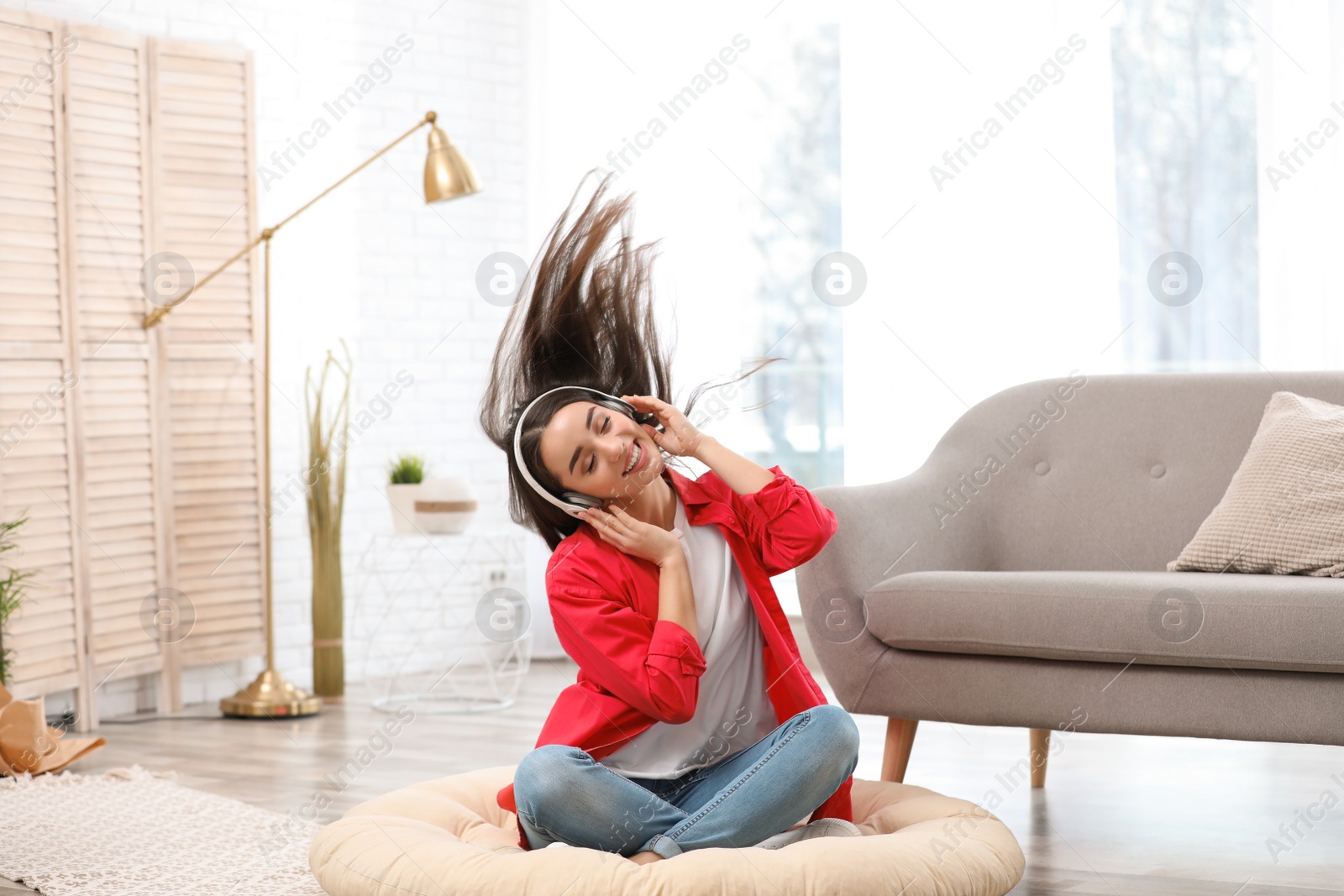 Photo of Young woman with headphones enjoying music on floor in living room