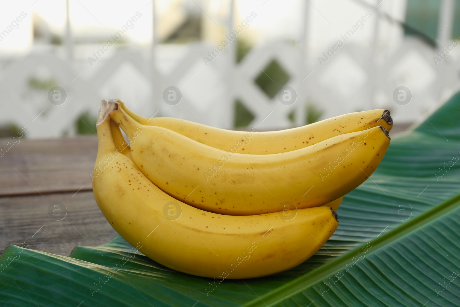 Photo of Delicious bananas and green leaf on wooden table