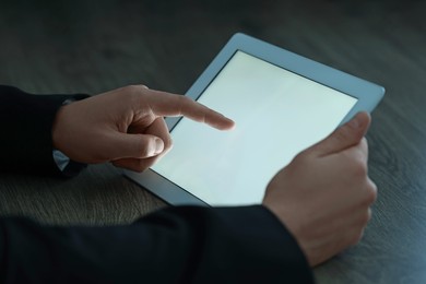 Man using tablet at wooden table, closeup view