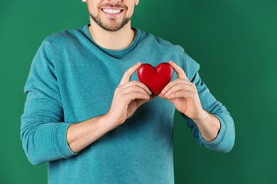 Man holding decorative heart on color background, closeup