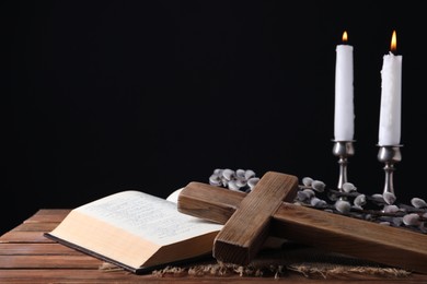 Photo of Burning church candles, cross, Bible and willow branches on wooden table