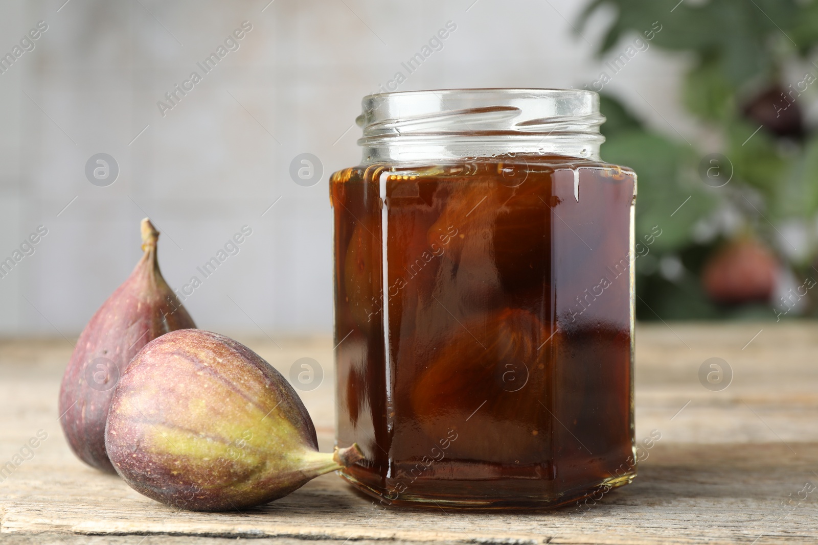 Photo of Jar of tasty sweet jam and fresh figs on wooden table