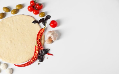 Fresh pizza dough and products on white background, flat lay. Space for text