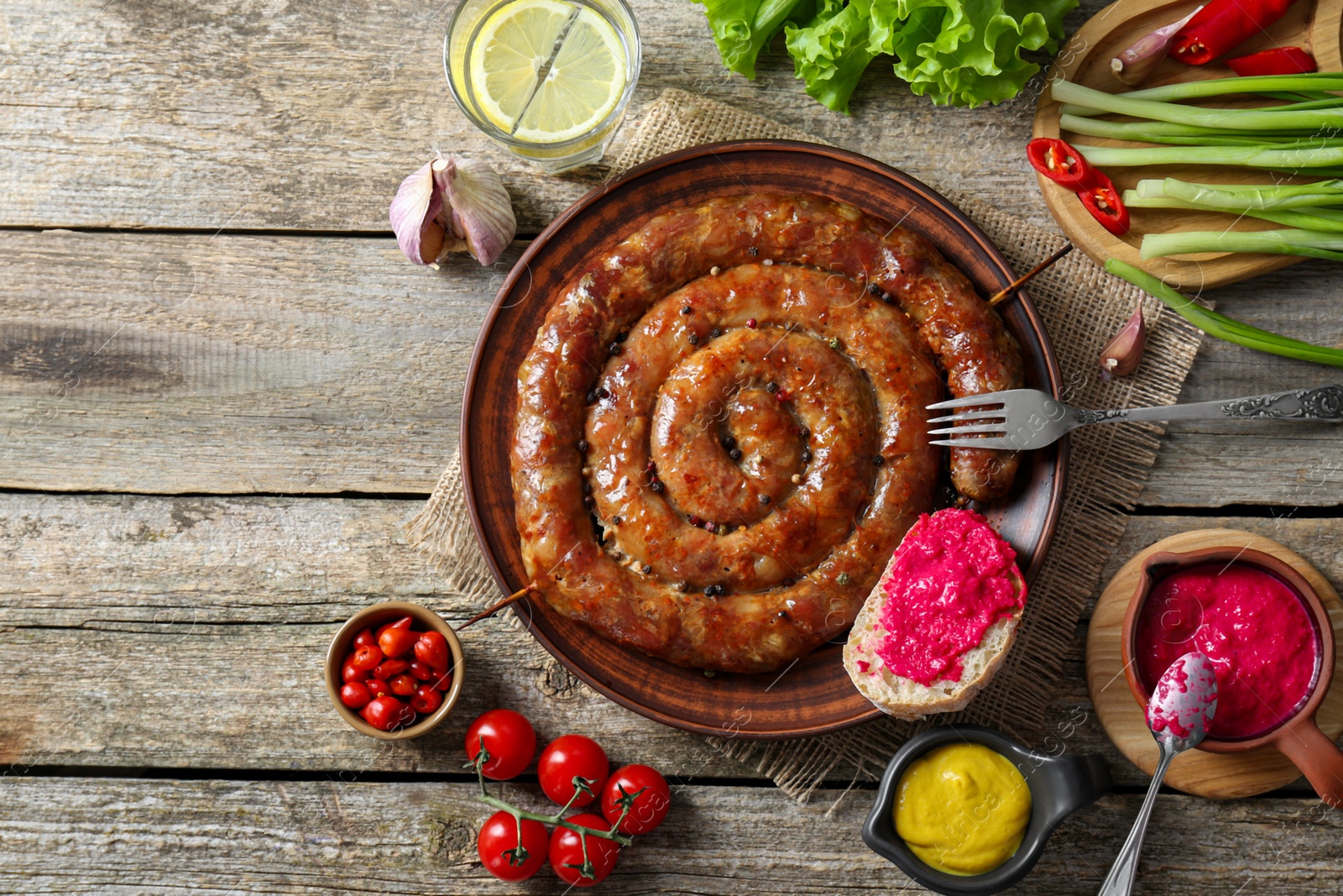 Photo of Tasty homemade sausages served on wooden table, flat lay