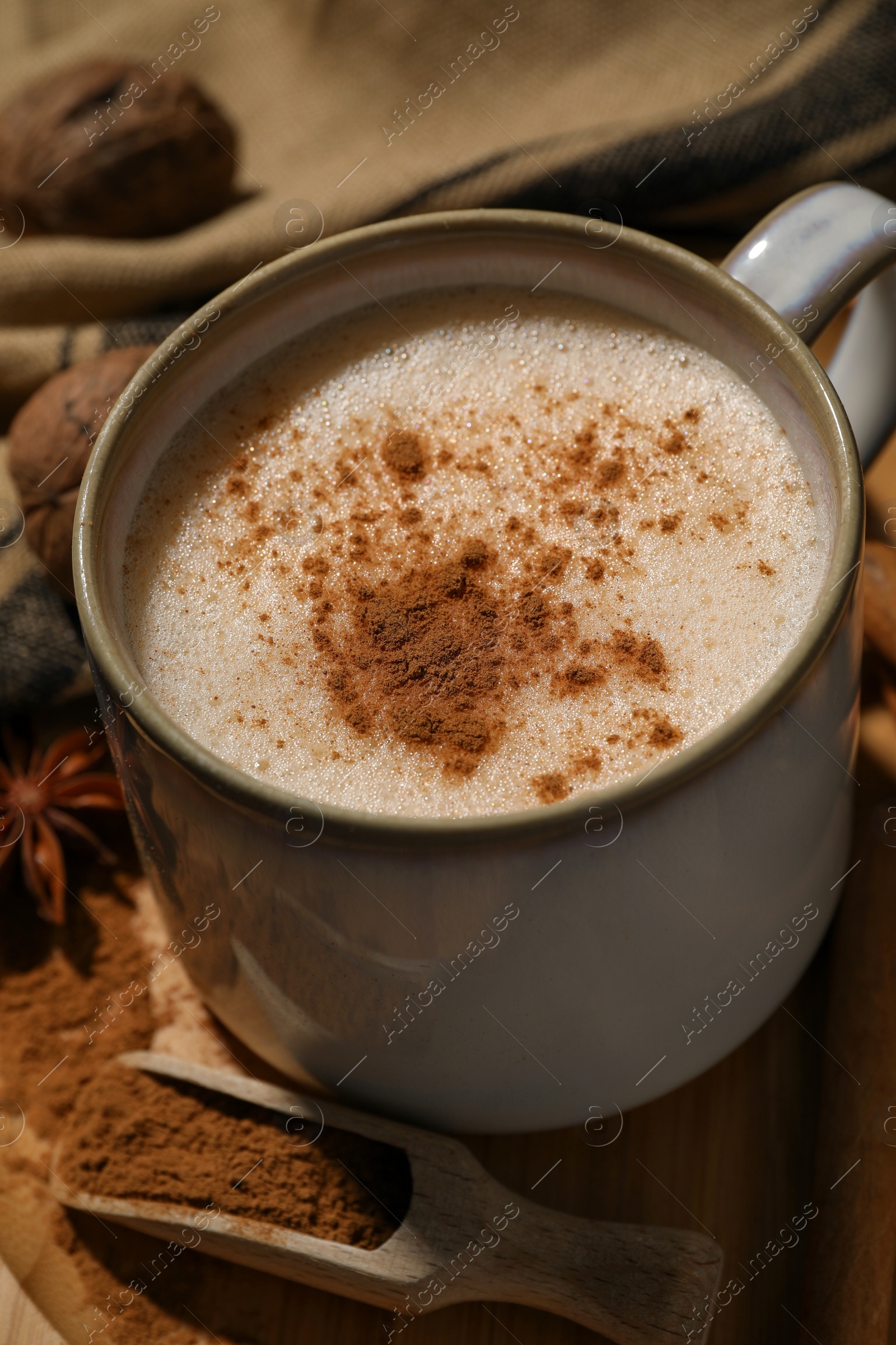 Photo of Cup of delicious eggnog with spices on wooden table