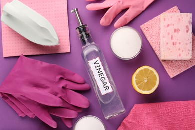 Photo of Eco friendly natural cleaners. Flat lay composition with bottle of vinegar and gloves on purple background