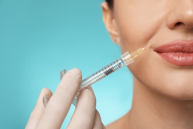 Photo of Beautiful woman getting facial injection on light blue background, closeup. Cosmetic surgery