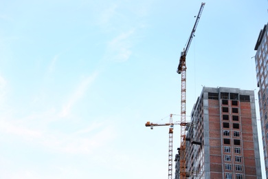 Photo of Construction crane and unfinished building against blue sky. Space for text