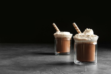 Glasses with delicious coffee drink on grey table against black background. Space for text